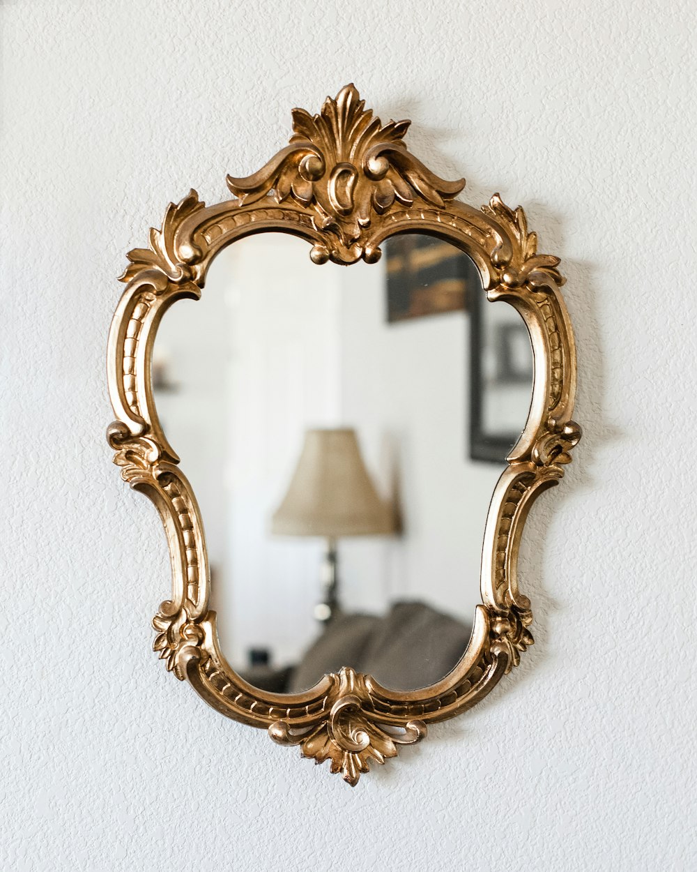 a mirror hanging on a wall next to a lamp