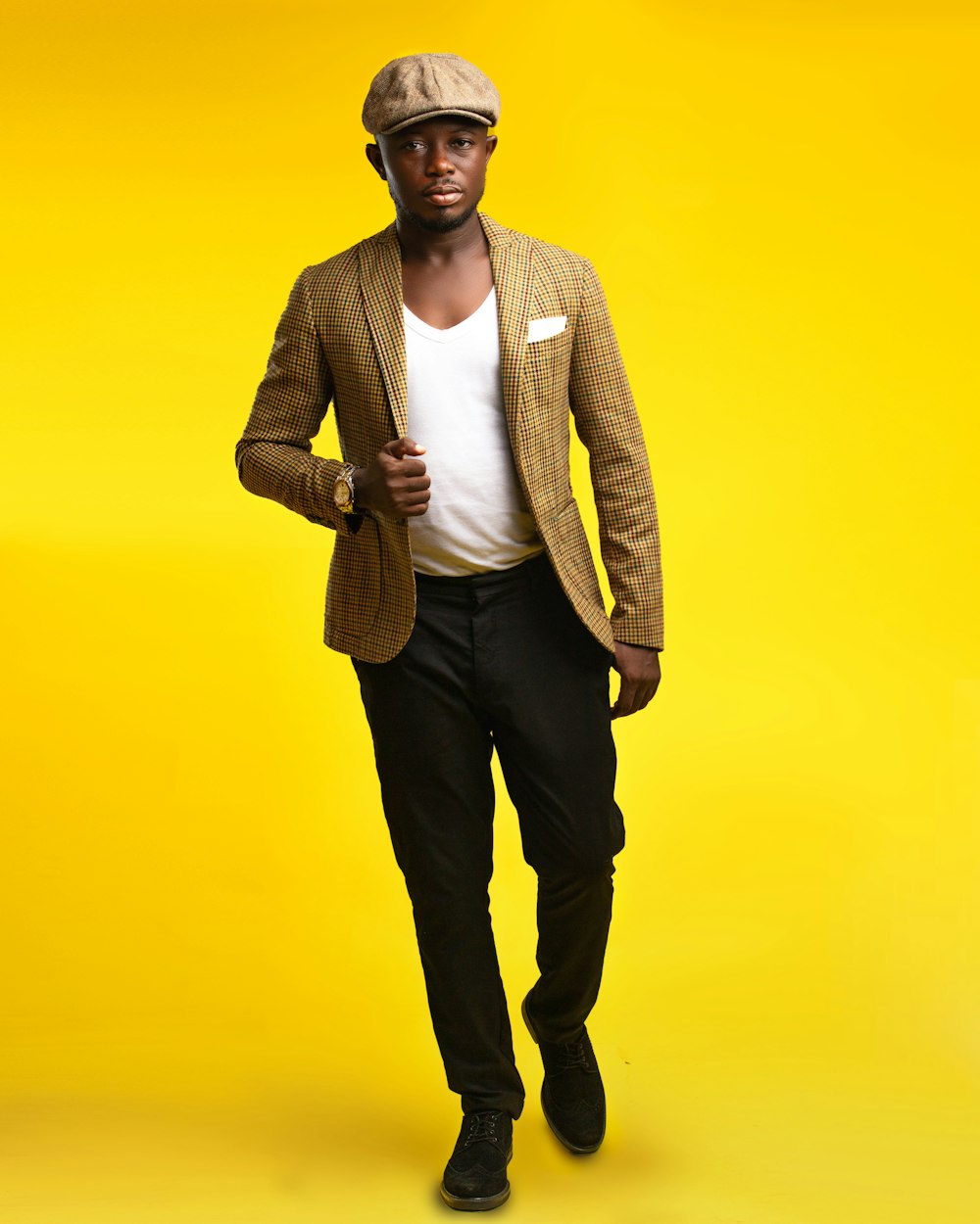 a man in a suit and hat standing in front of a yellow background