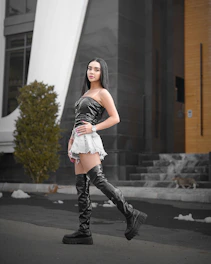 A stylish young woman wearing a sleek black miniskirt and crop top, posing confidently in a modern urban setting.