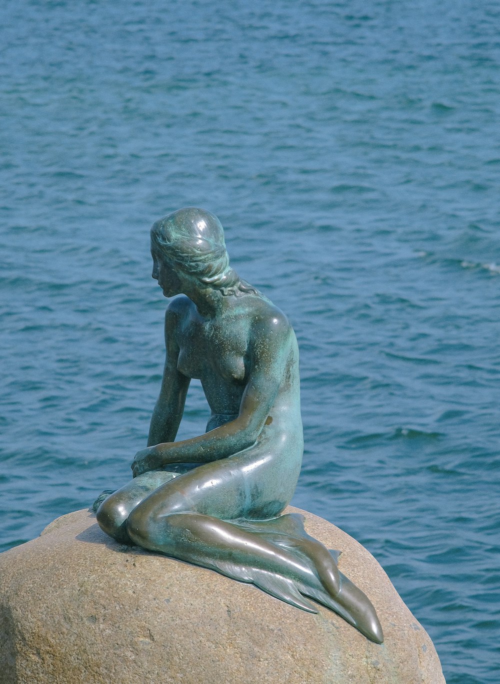 a statue of a woman sitting on top of a rock