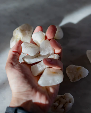 A serene morning scene with a hand holding the holy stone against a soft light background.