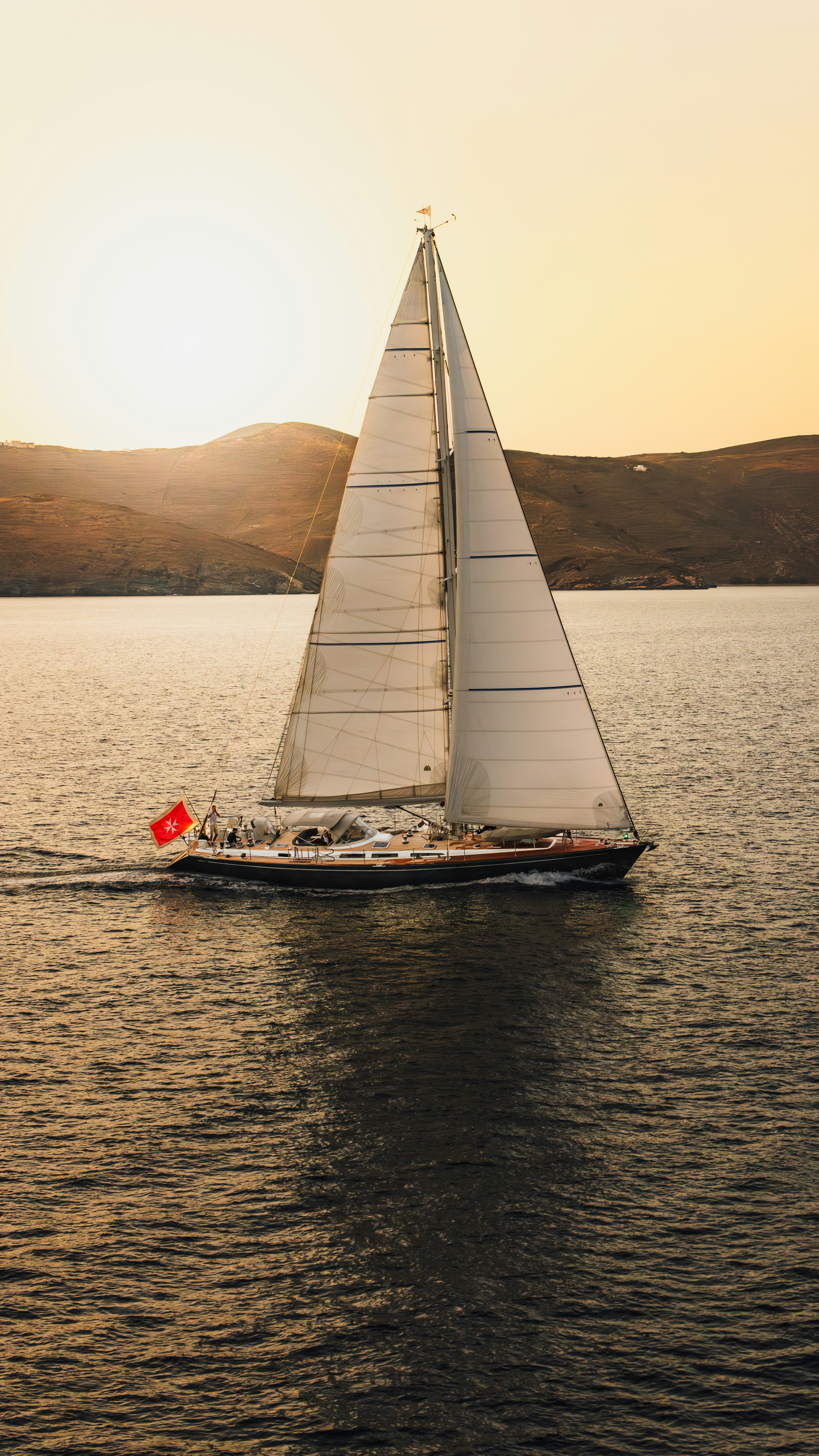 a sailboat with a red flag is in the water