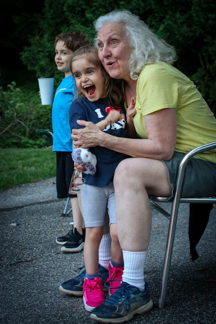 a woman sitting on a chair next to her granddaughter laughing