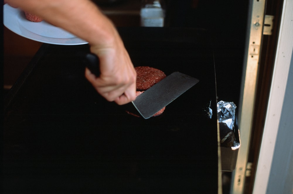 a person using a knife to cut a piece of food