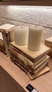 A serene stack of spiritual books beside a softly glowing candle on a wooden table.