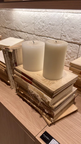 A gentle stack of neutral-toned wellness books beside a softly flickering candle.