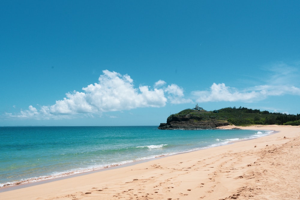 a sandy beach with a small island in the distance