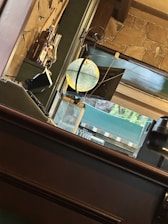 A cozy interior with a globe suspended on a stand, surrounded by stone wall decor and shelves holding various bottles. Light filters in through a large window, creating a warm and inviting atmosphere.