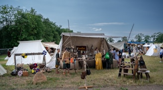 A lively medieval market scene with colorful tents and people in period costumes.