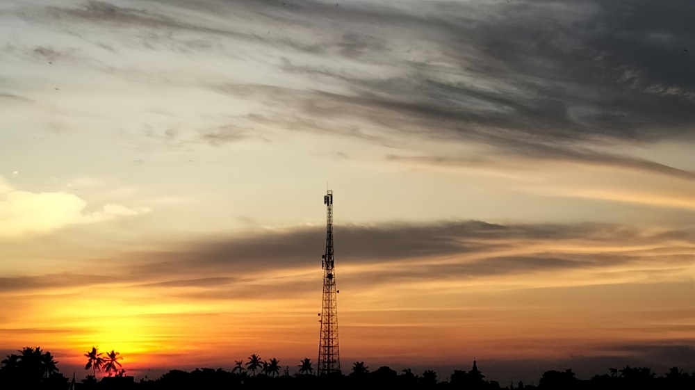 a very tall tower sitting in the middle of a sunset