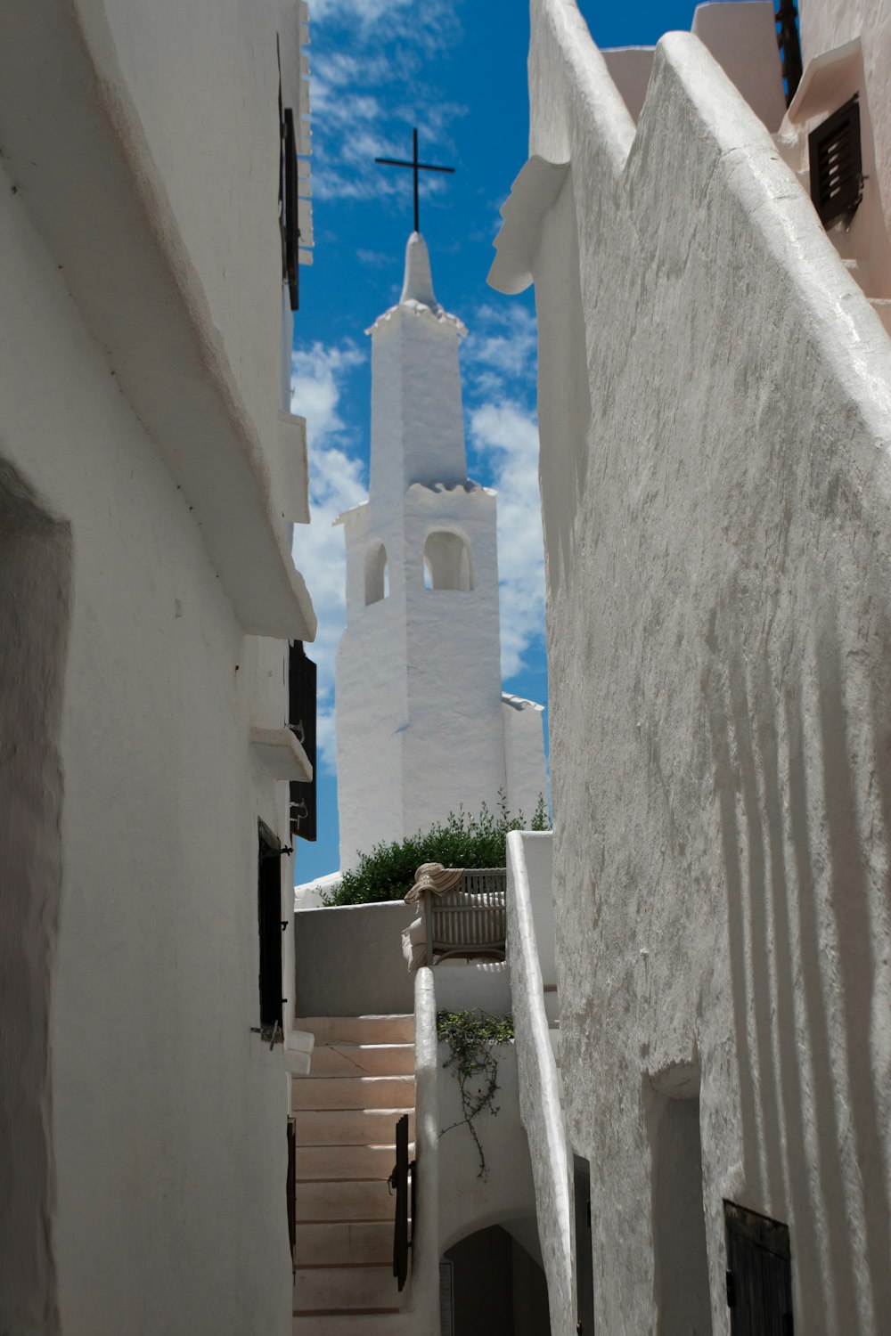 a narrow alley with a steeple in the background