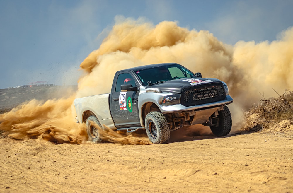 a pickup truck driving through a dirt field