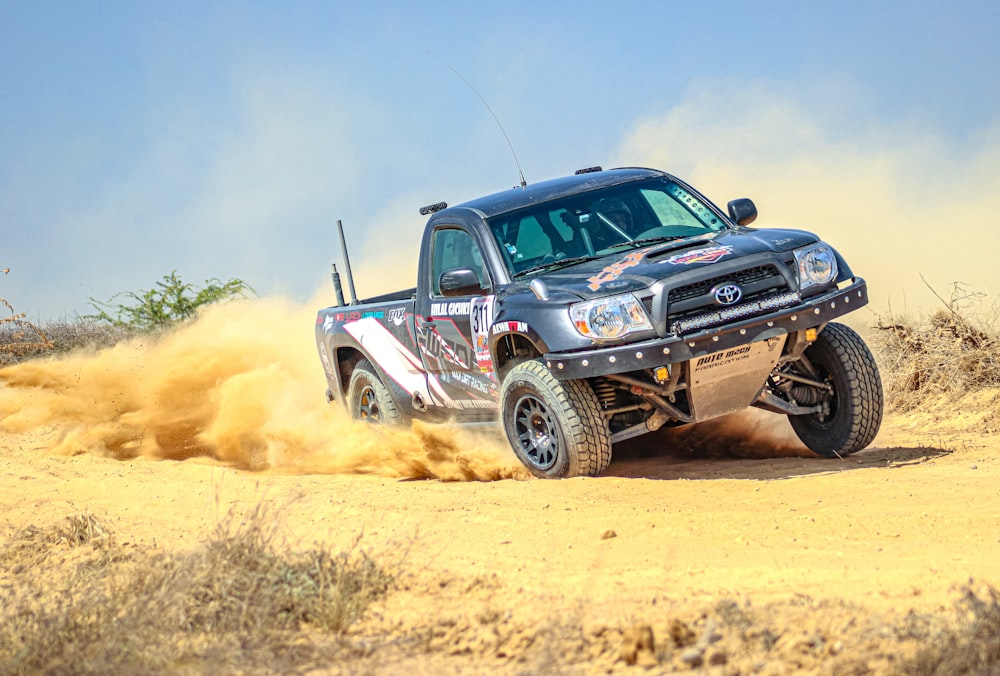 a black truck driving through a dirt field