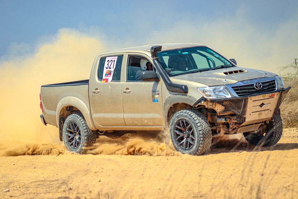 a silver truck driving on a dirt road