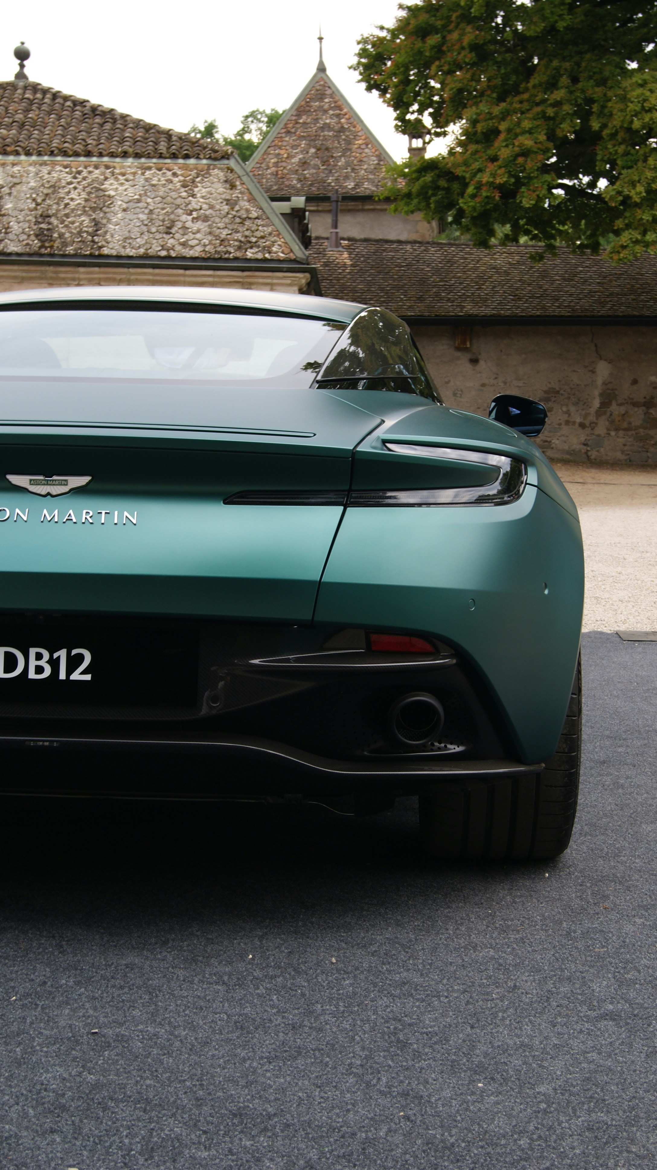 Silver Aston Martin DB12 on misty British countryside road, elegant sports GT, sophisticated atmosphere
