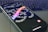 A smartphone lies on a laptop keyboard with the screen displaying swirling text that reads 'SAY MORE' and 'THREADS' in colorful letters. The Instagram logo is visible at the bottom of the phone's screen.