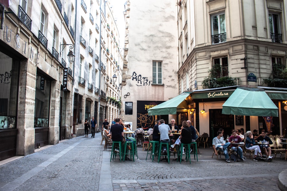 a group of people sitting at tables in an alleyway