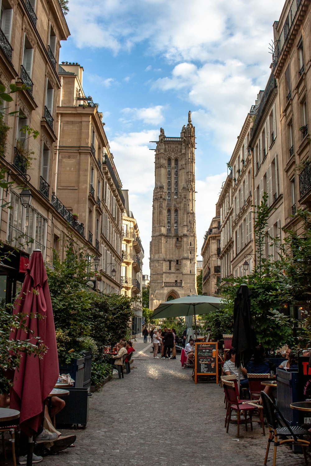 a narrow city street with tables and chairs