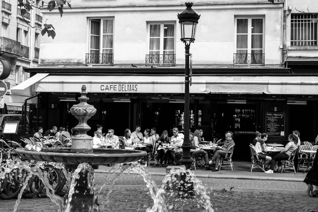 a black and white photo of people sitting at tables in front of a building,