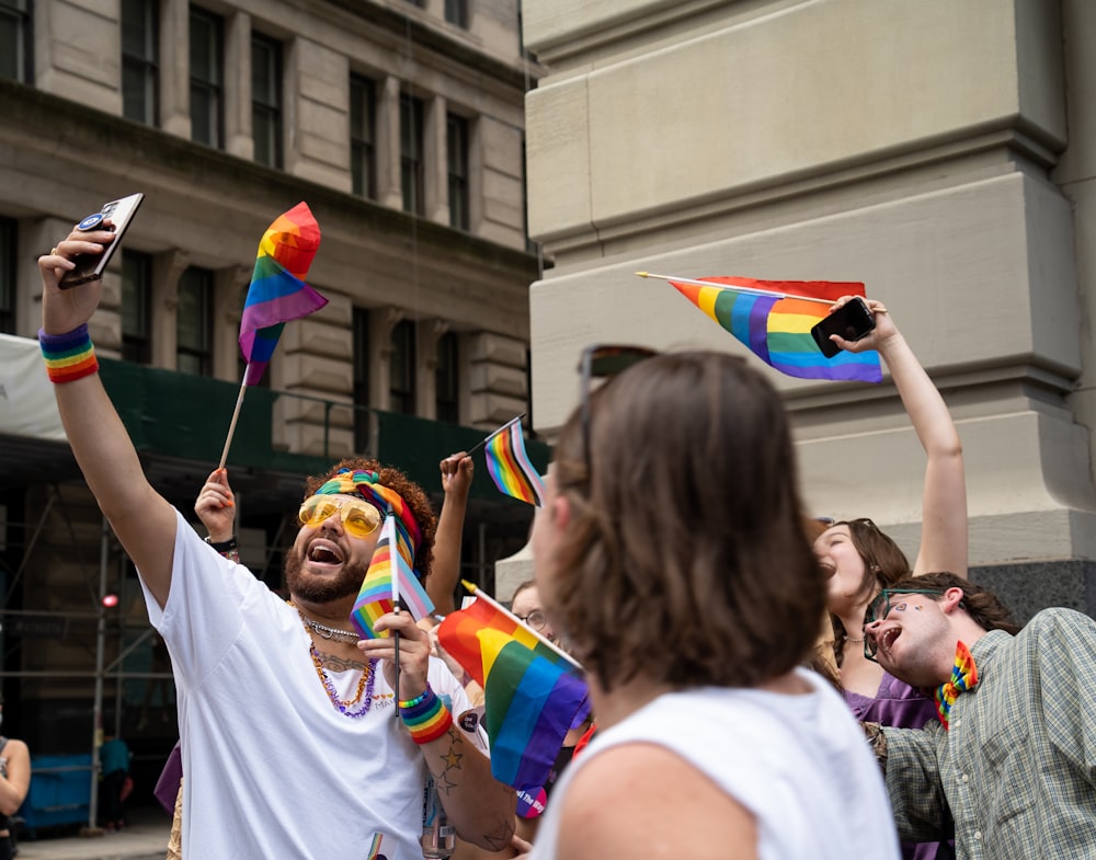 a group of people standing around each other holding rainbow flags