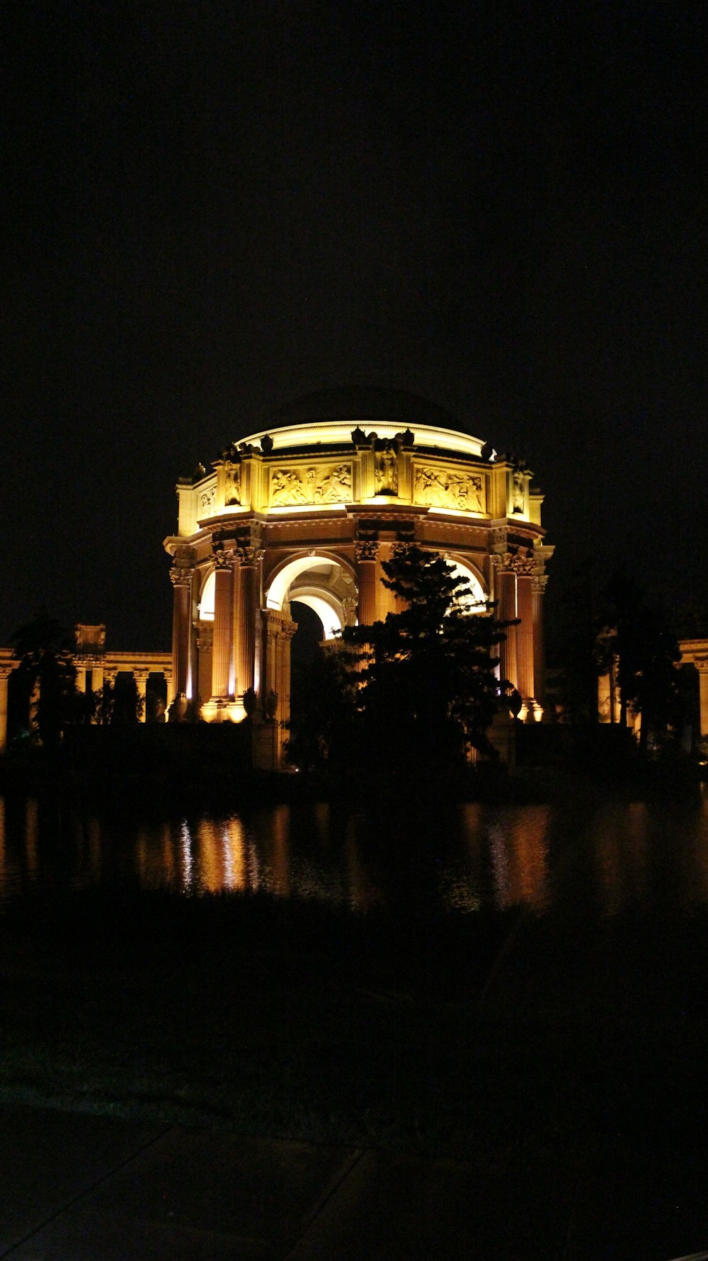 a building lit up at night with a pond in front of it