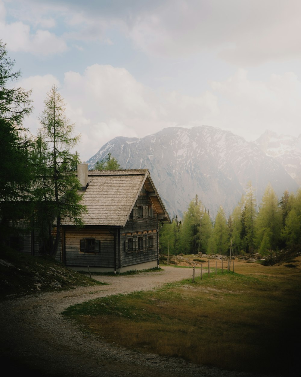 a house in the middle of a field with mountains in the background