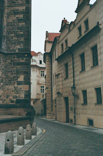A narrow cobblestone street lined with restored historic buildings under soft daylight.