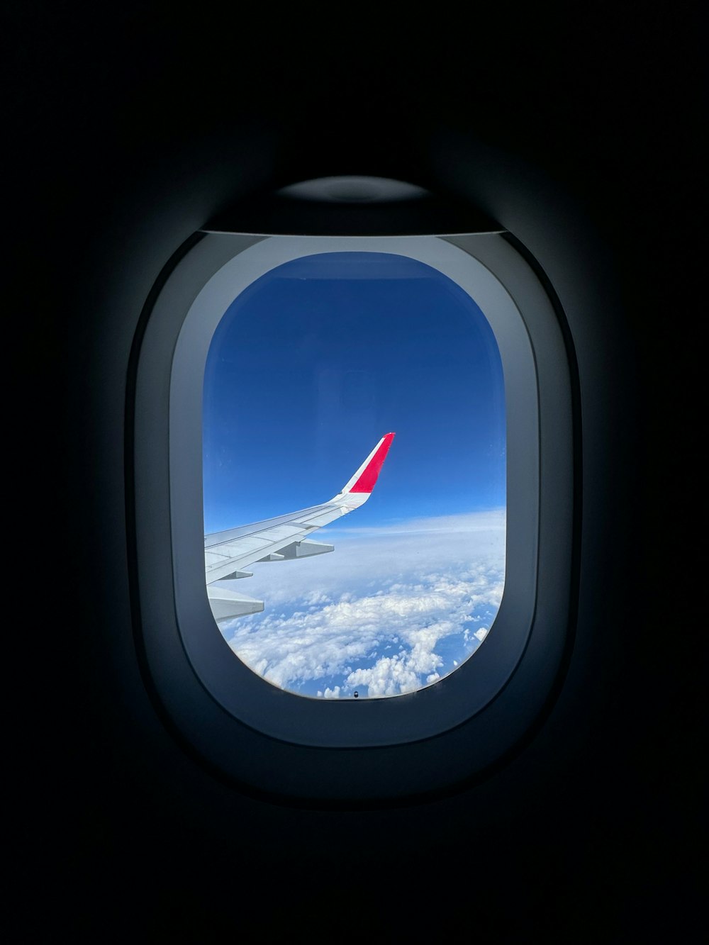Blick durch ein Fenster auf die Tragfläche eines Flugzeugs