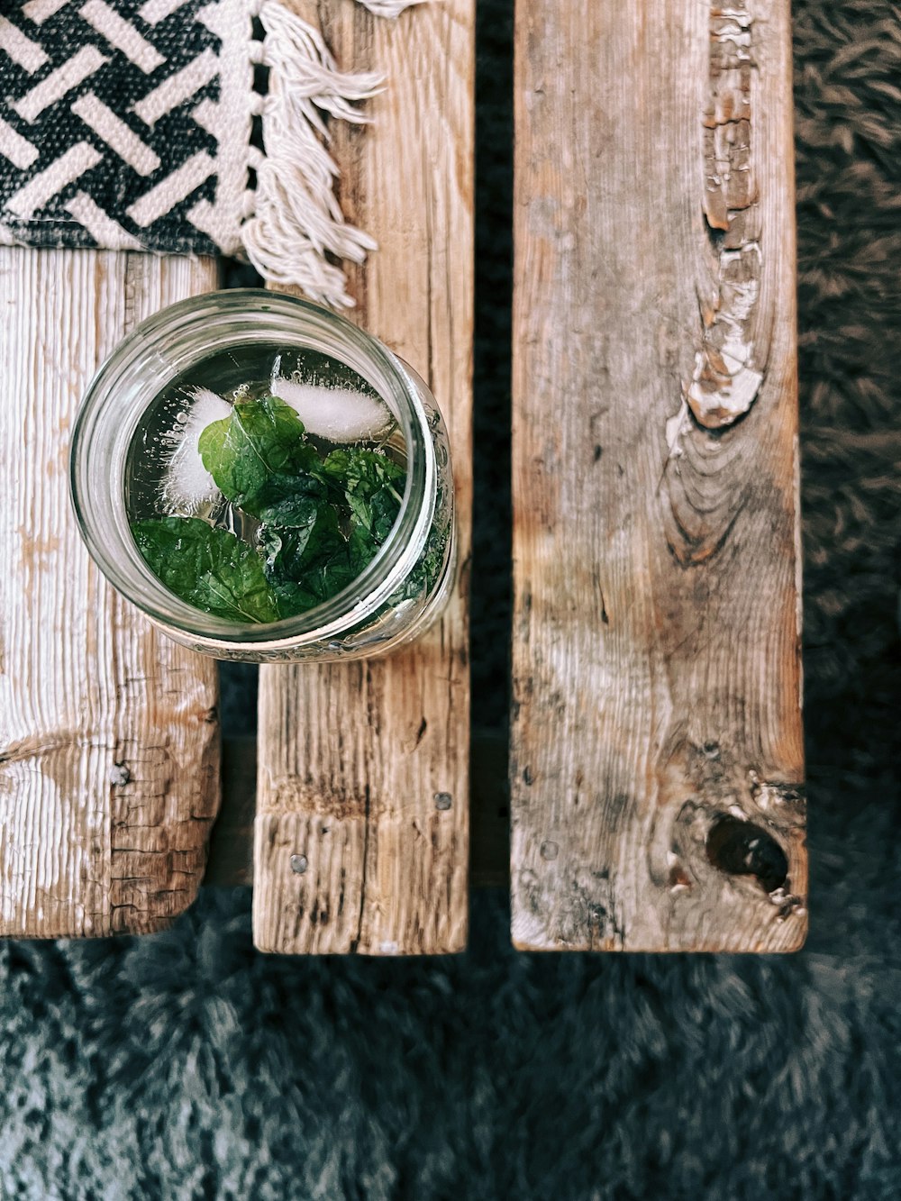 a mason jar filled with ice and mint on top of a wooden pallet