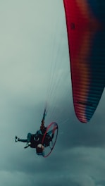 Pilot preparing a paramotor for a personalized flight route over a lively event.