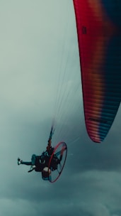 Pilot preparing a paramotor for a personalized flight route over a lively event.