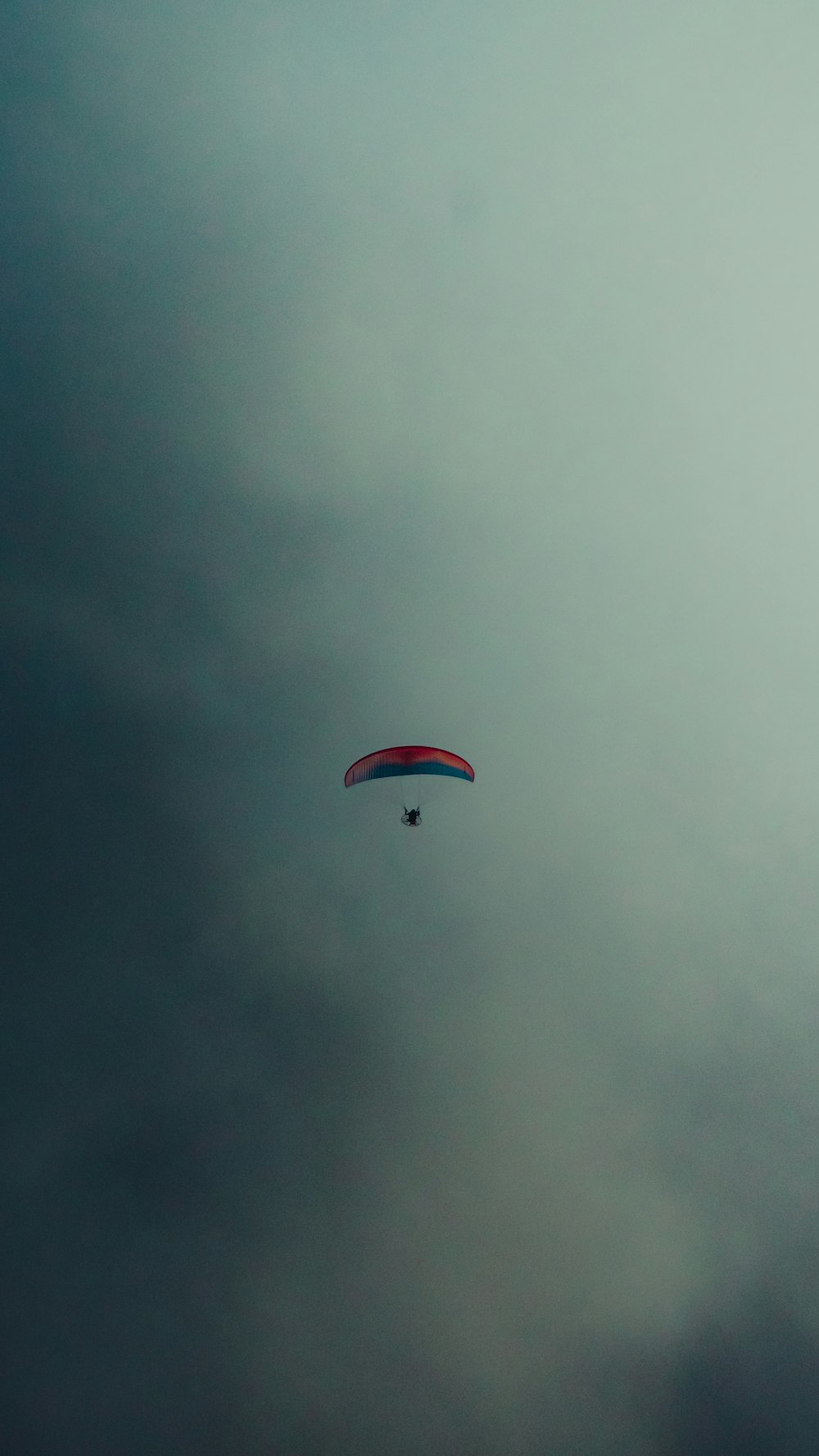 a paraglider flying through a cloudy sky