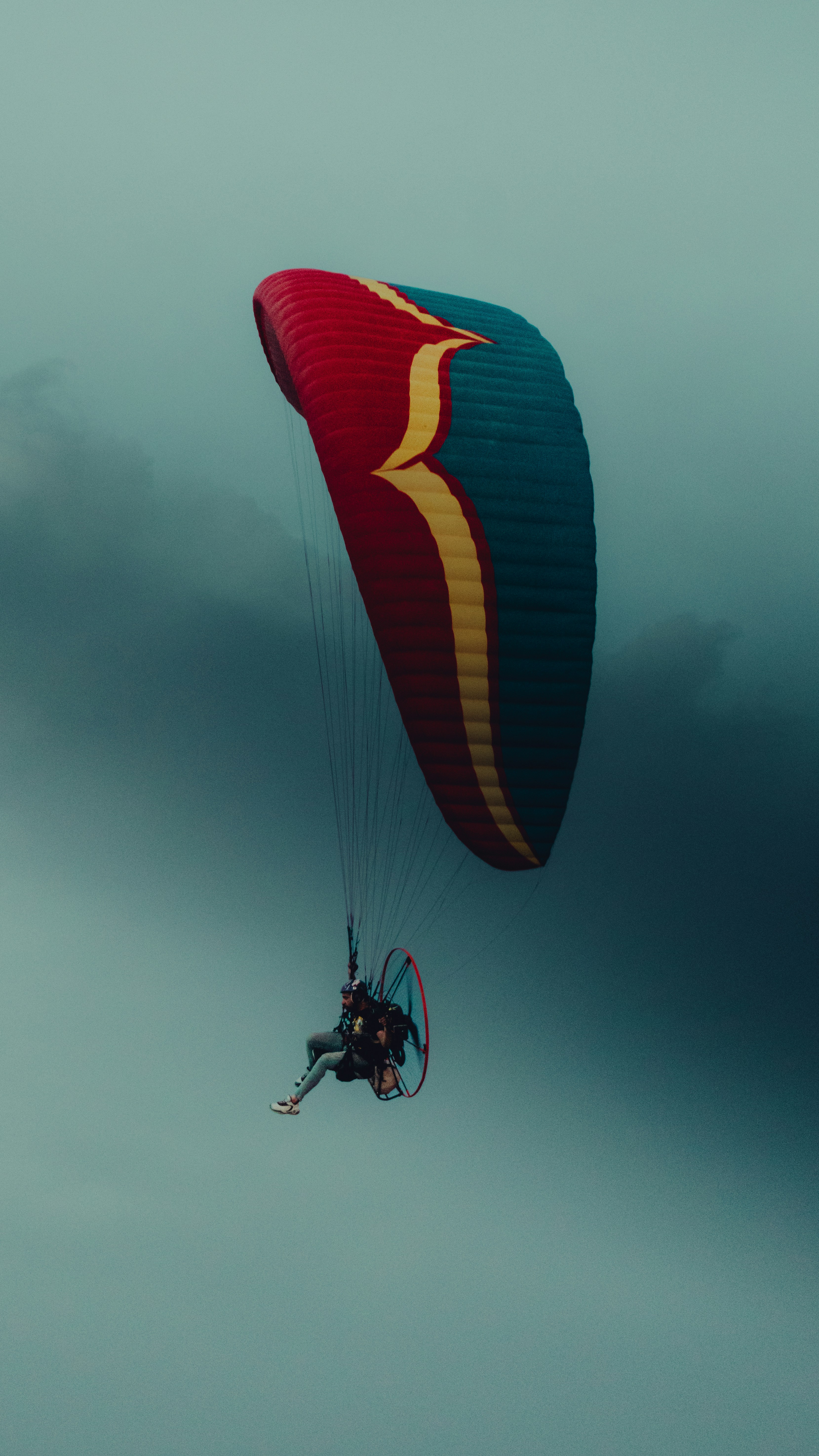 a person is parasailing in the sky on a cloudy day