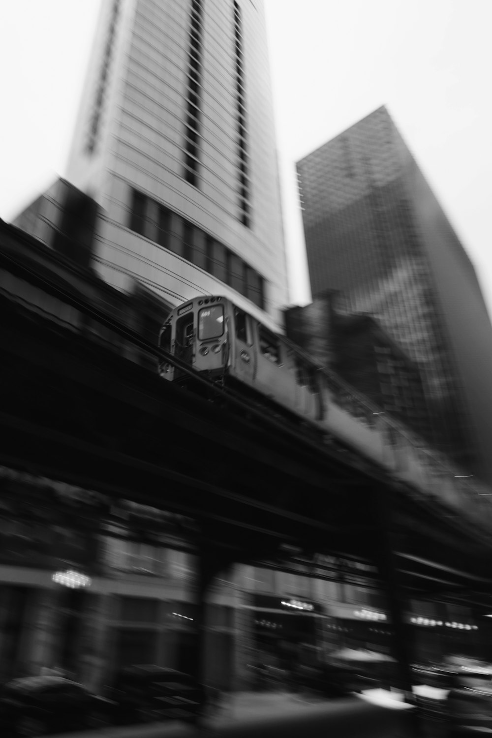 a black and white photo of a train passing by a tall building