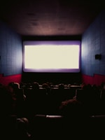 a large screen in a dark room with people watching it