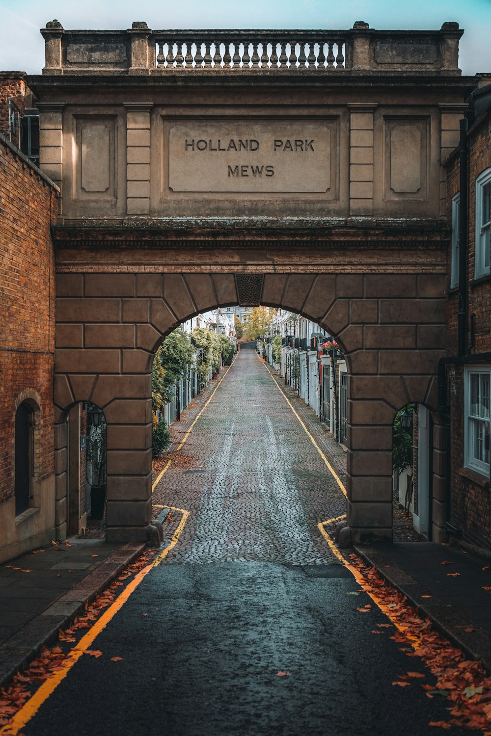 a brick archway with a sign on it that says holland park mews