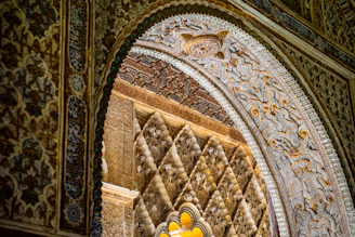Close-up of intricate Islamic geometric patterns carved in gold on a mosque's archway.