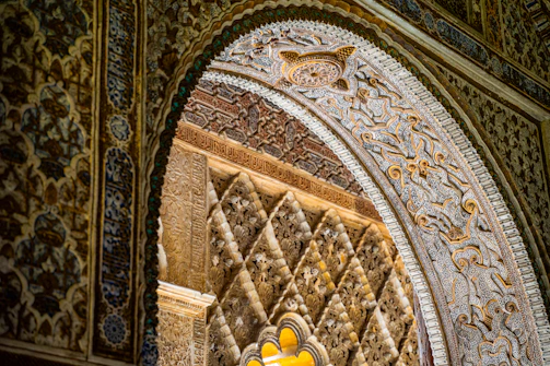 Close-up of intricate Islamic geometric patterns carved in gold on a mosque's archway.