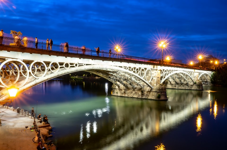The Triana Bridge lit up over the Guadalquivir river at night