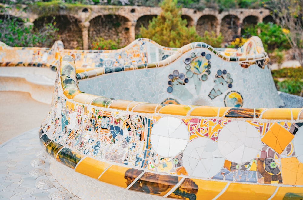 a yellow and white tiled bench in a park