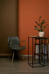 A sleek hexagonal side table made of rich wood and metal accents beside a comfy chair.