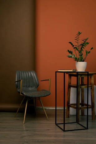 A sleek metal side table beside a comfy chair with a floor mat set underneath.