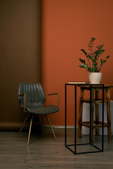 A sleek luxury metal side table with a brushed finish, styled in a cozy living room corner.