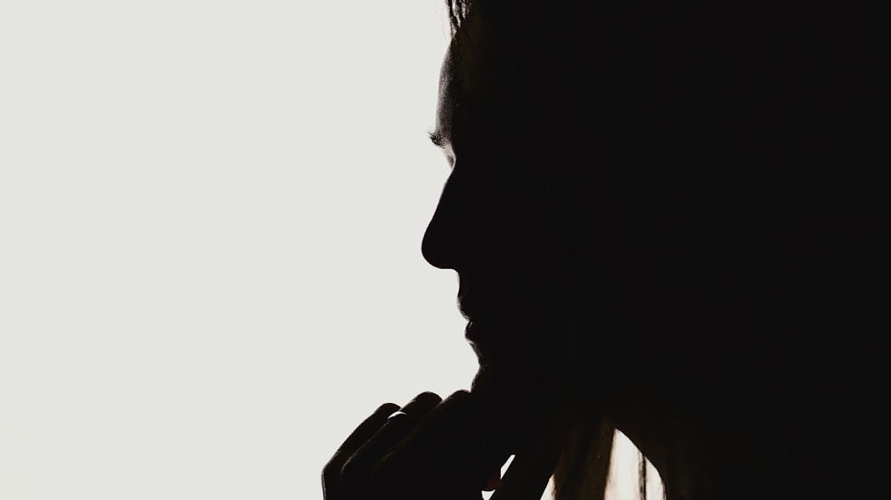 a silhouette of a woman holding her hand to her mouth