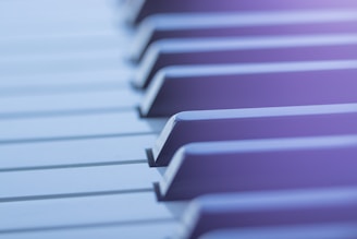 Close-up view of piano keys with a soft focus and a gentle blur effect. The lighting creates a serene and tranquil atmosphere.
