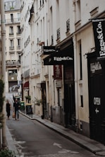 a couple of people walking down a street next to tall buildings