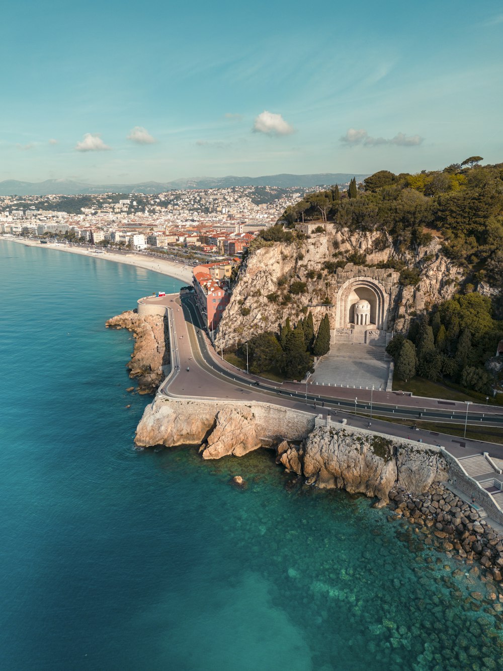 an aerial view of a road next to a body of water