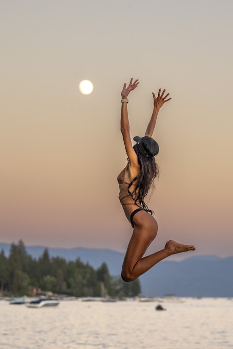 a woman in a bikini jumping into the air