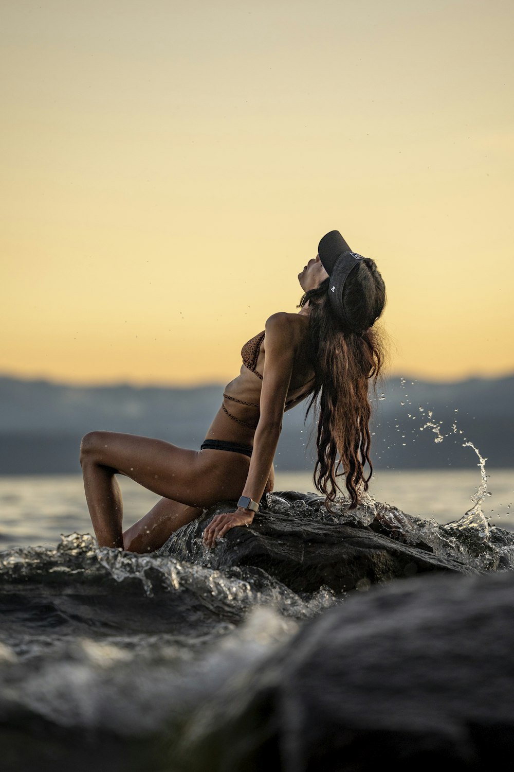 a woman sitting on a rock in the water