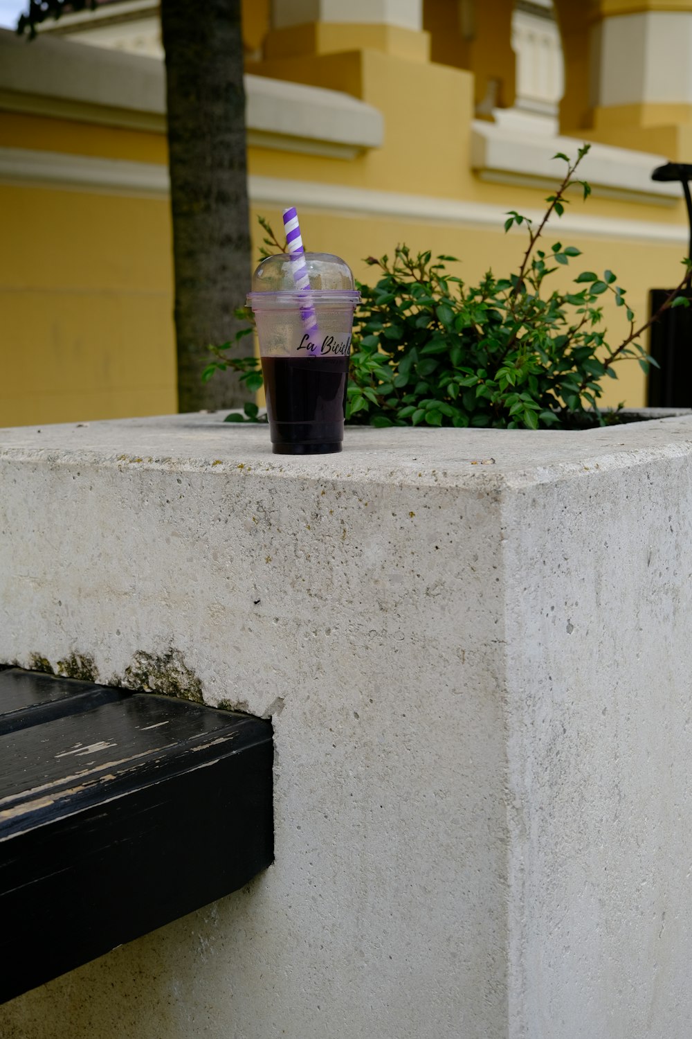 a cup of drink sitting on top of a cement wall